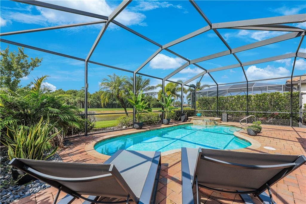 Screened outdoor pool area featuring a curved pool with an integrated spa