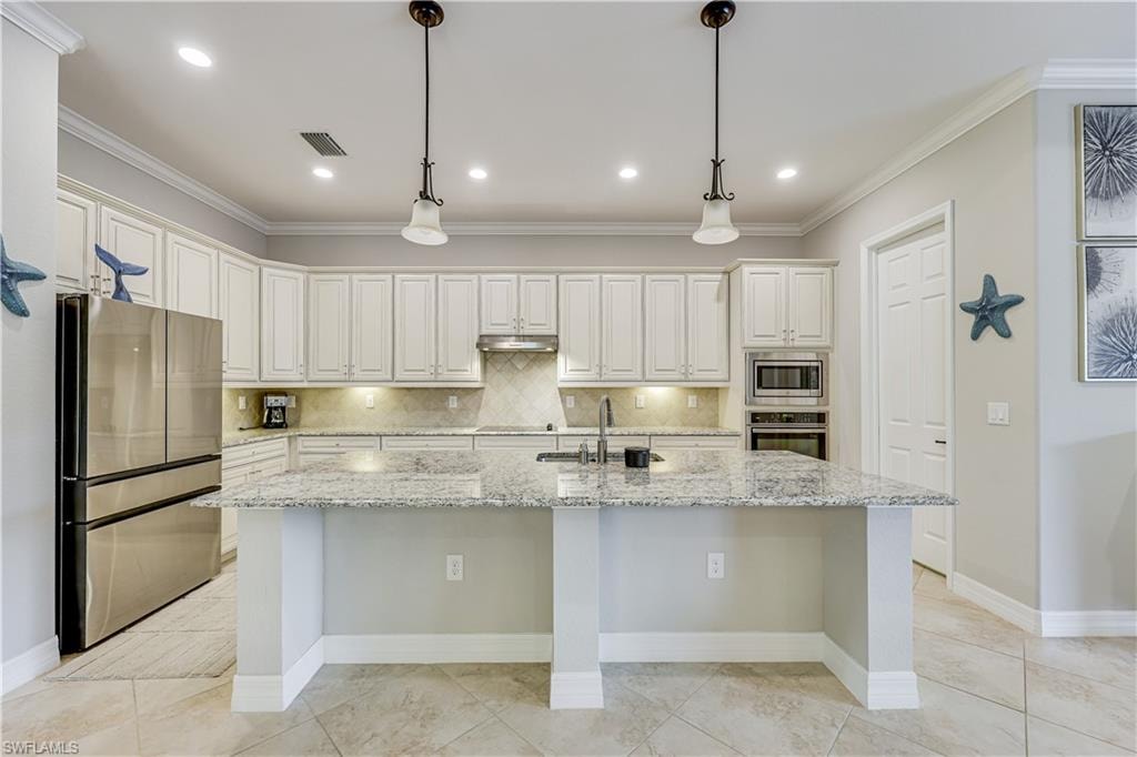 Spacious kitchen featuring an expansive island with a granite countertop, white cabinetry, built-in stainless steel appliances, and recessed lighting