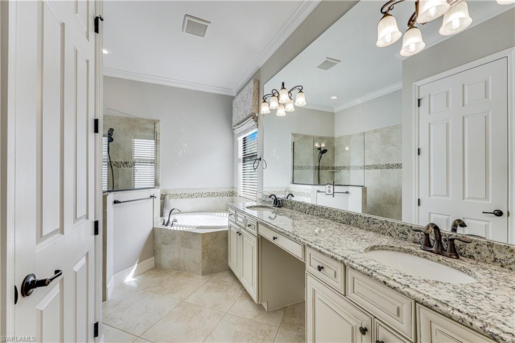 Bathroom featuring a double vanity with granite countertop, integrated sinks, and bronze-finish fixtures