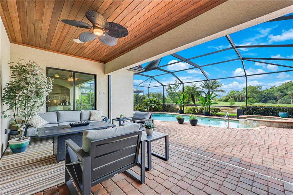 Expansive screened lanai featuring a paver patio, integrated swimming pool, and a jetted spa