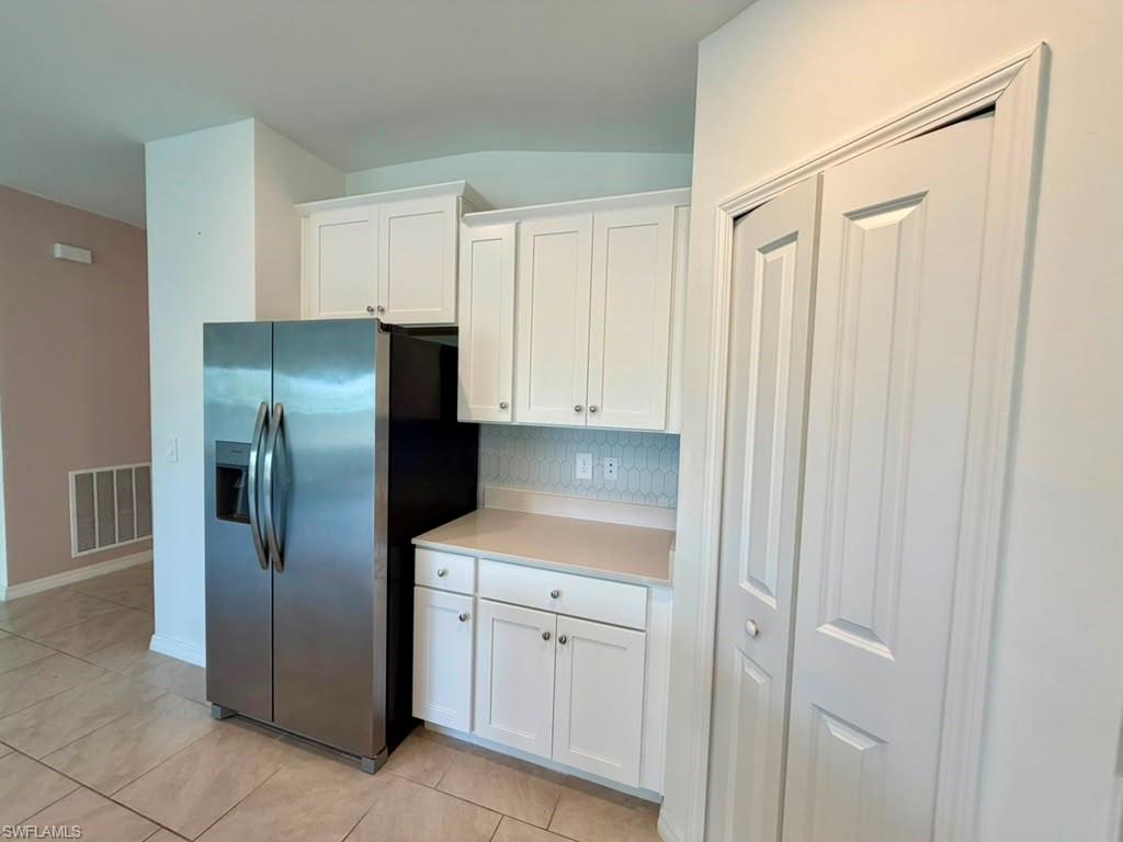 Contemporary kitchen featuring white shaker cabinetry, light-toned countertops, and a decorative tile backsplash