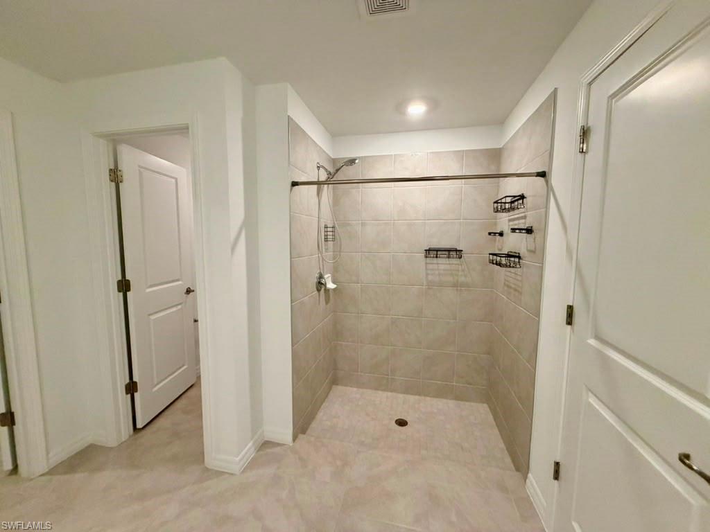 Walk-in shower with light-toned tile surround and flooring