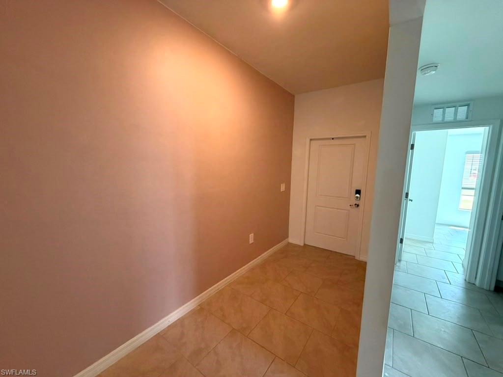 Entryway featuring neutral-toned wall, tile flooring, and a flush-mount light fixture