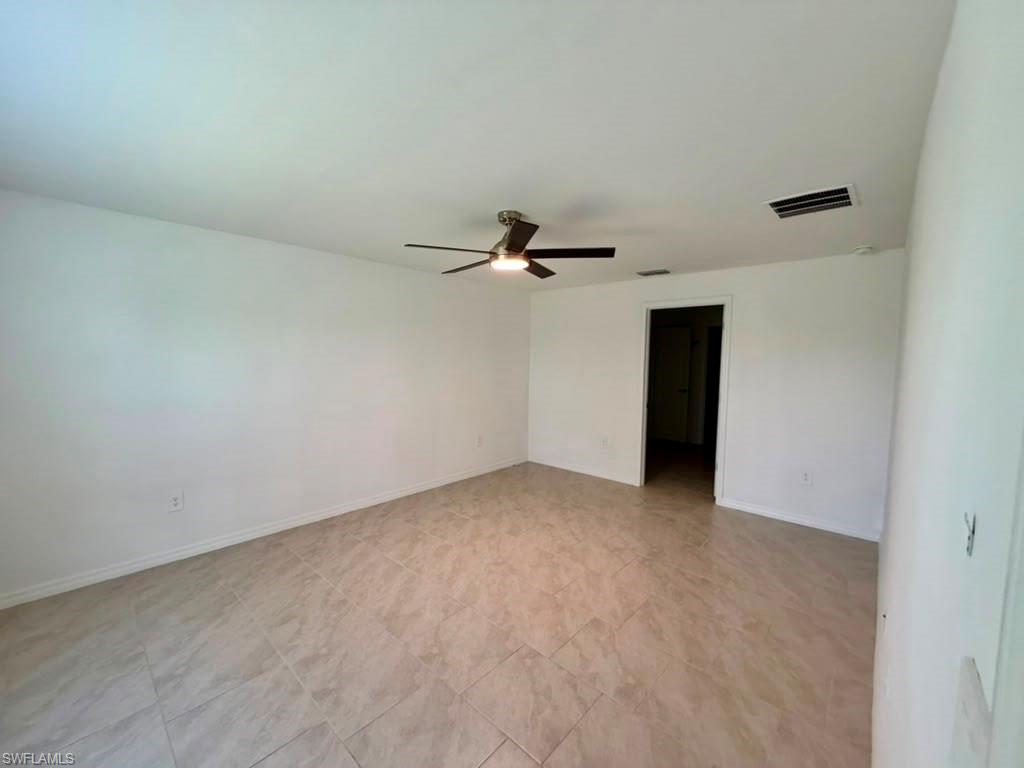 Spacious interior room featuring light-toned tile flooring and crisp white walls