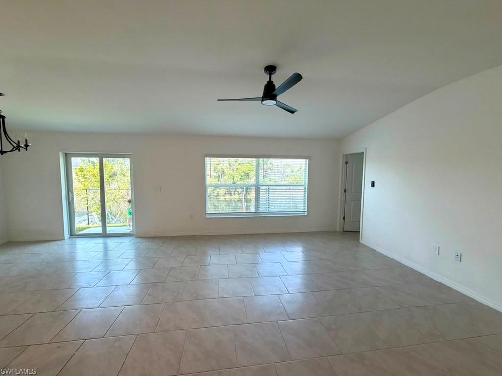 Spacious interior with neutral-toned tile flooring, white walls, and a modern ceiling fan