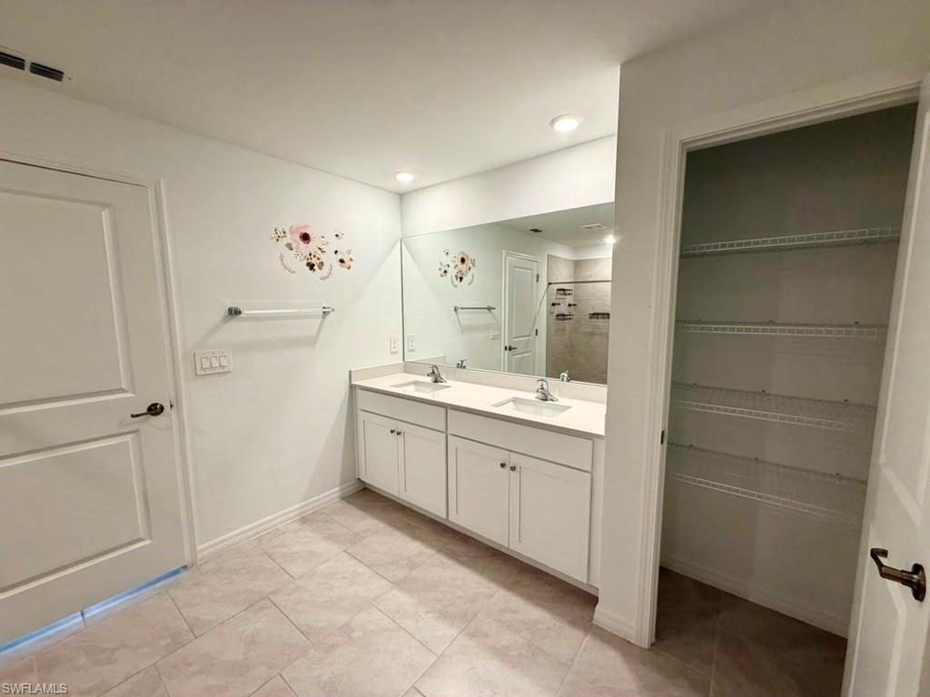 Bathroom featuring a dual-sink vanity with white cabinetry and a full-width mirror