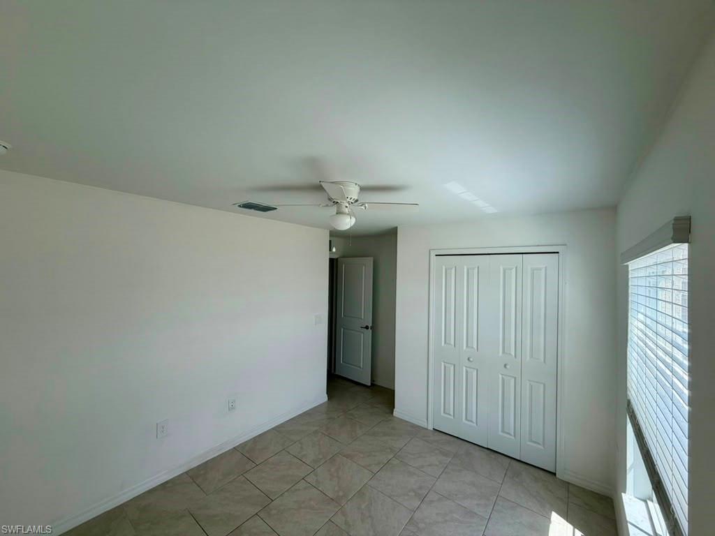 Neutral-toned room featuring a ceiling fan, tiled flooring, and a window with blinds