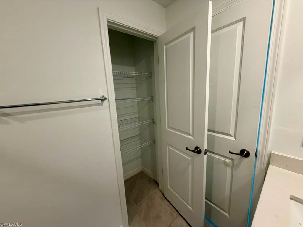Recessed pantry with wire shelving, light-toned tile flooring, and crisp white trim