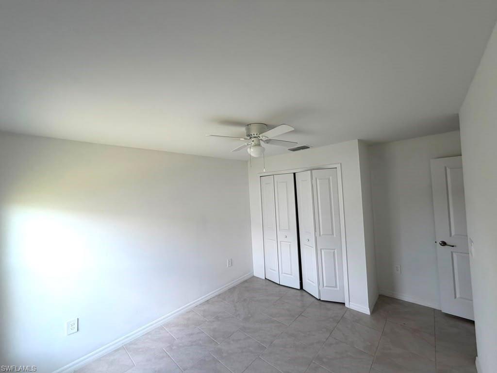 Interior room featuring light-toned tile flooring, white walls, and a ceiling fan