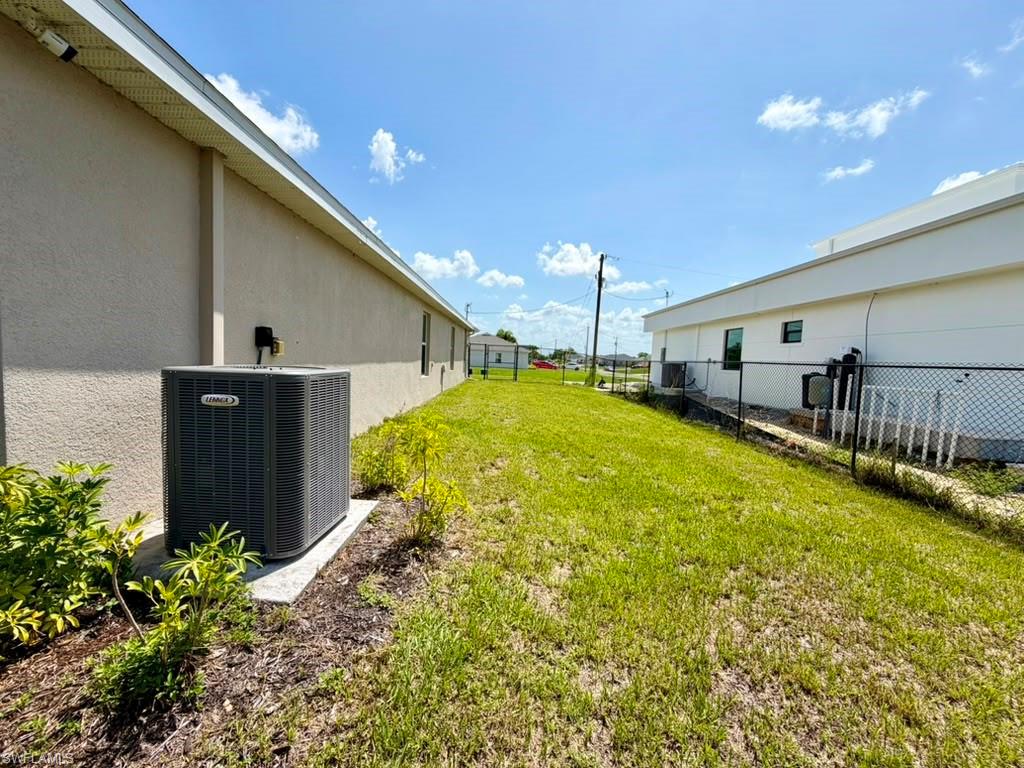 Spacious side yard featuring green grass, a stucco exterior, and a visible HVAC unit