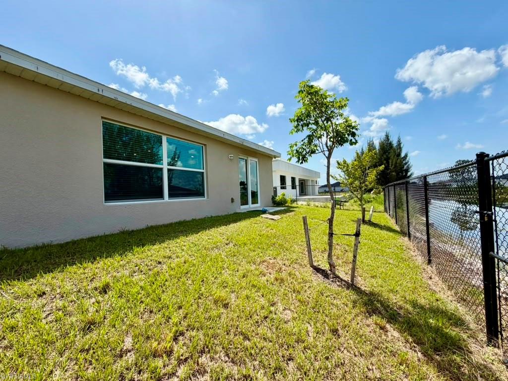 Rear exterior featuring a stucco finish, multiple windows, and a sliding glass door
