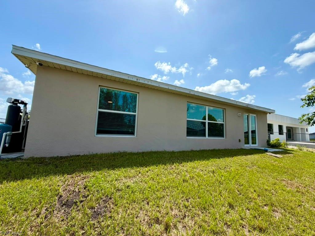Exterior stucco finish, multiple windows with blinds, and a glass-paneled entry door