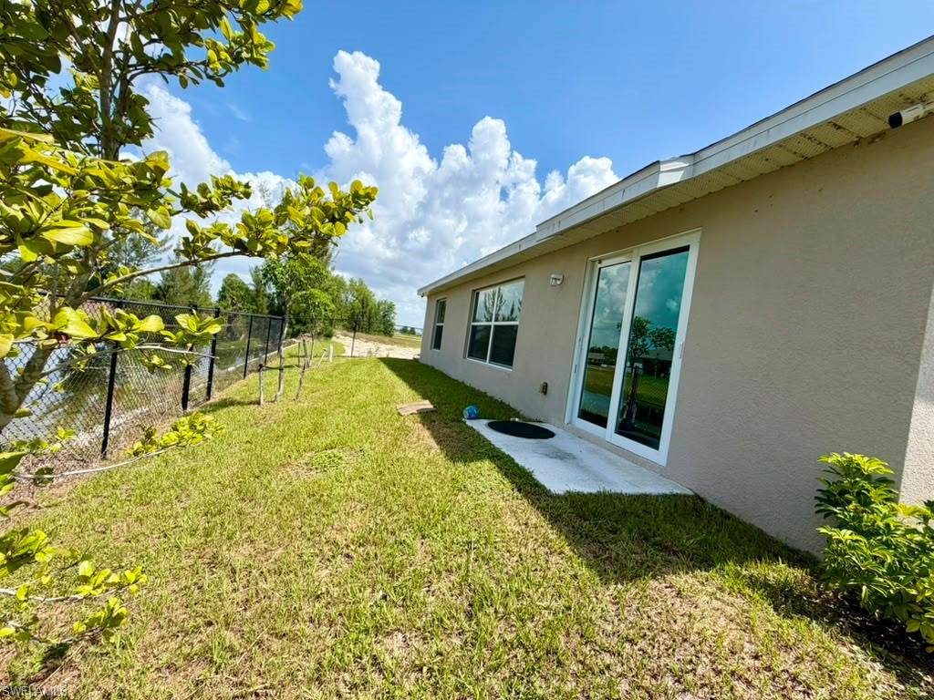 Stucco exterior featuring a glass sliding door, multiple windows, and a concrete patio