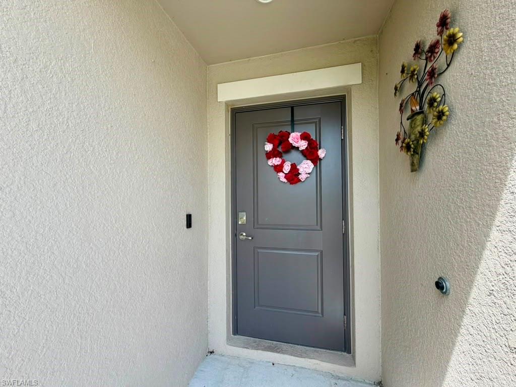 Recessed entry featuring a paneled door, stippled stucco exterior, and overhead lighting