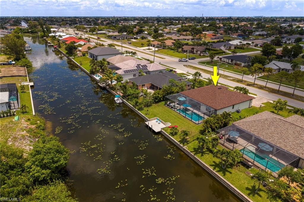 Waterfront property featuring a screened-in pool, private dock, and mature landscaping