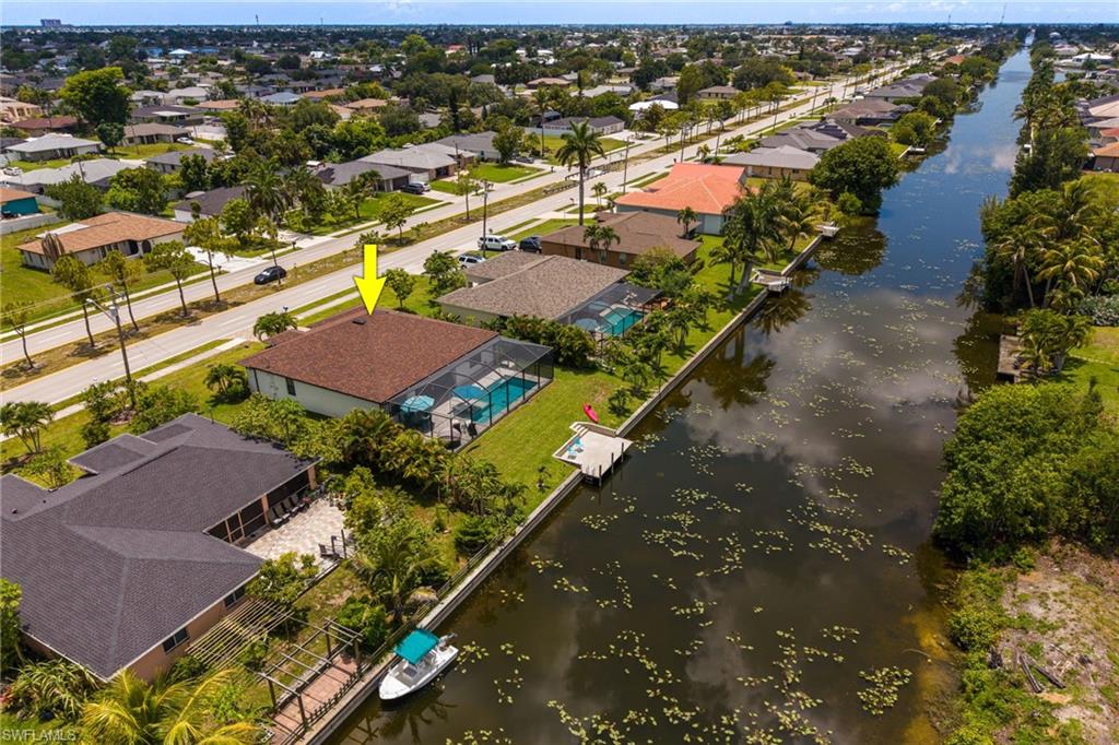 Waterfront property featuring a screened-in pool, private dock, and mature landscaping