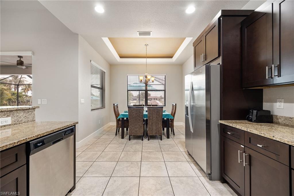 Kitchen and dining area featuring dark wood cabinetry, stainless steel appliances, and granite countertops
