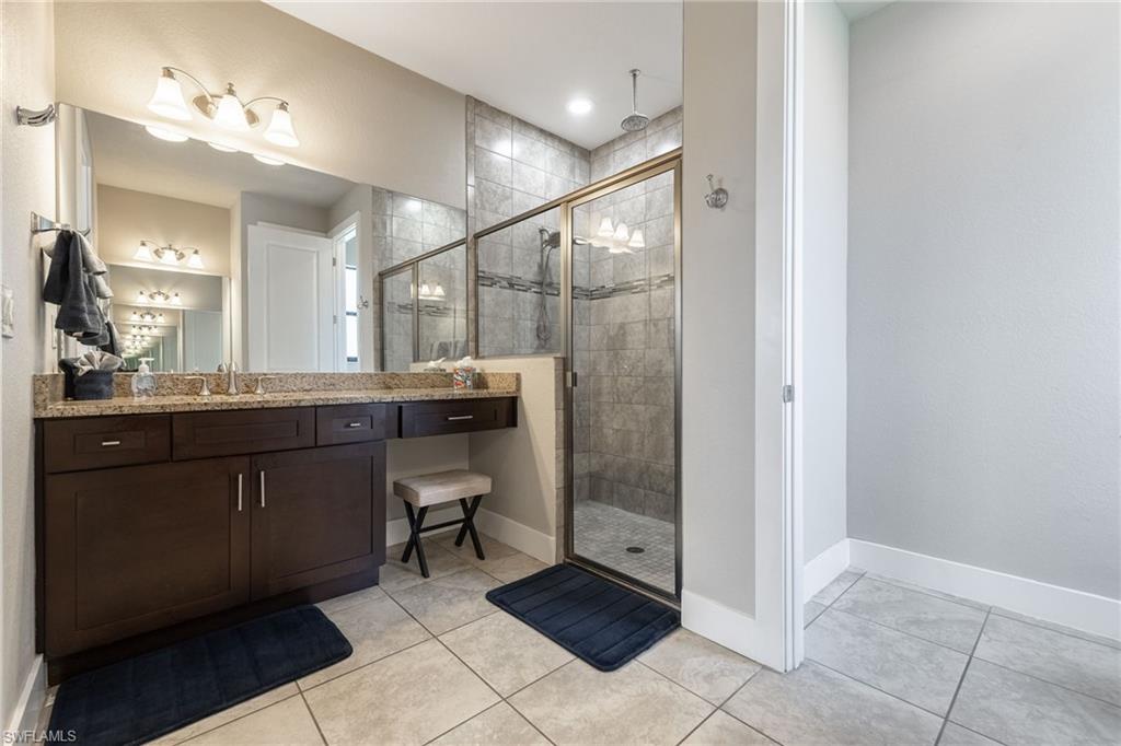 Bathroom featuring a dark wood finish vanity with a light-toned countertop, dual sinks, and a large mirror