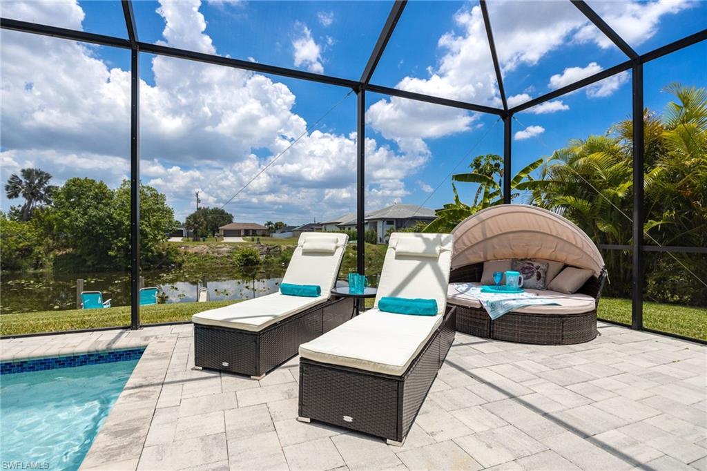 Screened outdoor living area featuring a paved patio and an in-ground swimming pool with blue tile accents