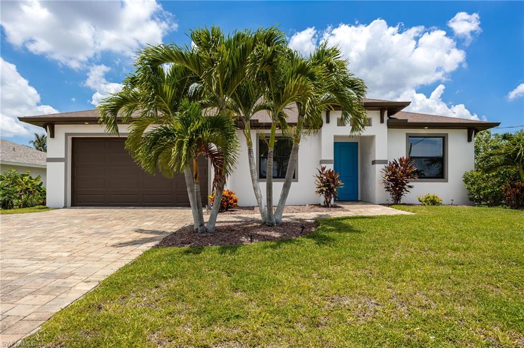 Contemporary single-story residence with a two-car garage, paver driveway, and a vibrant blue entry door