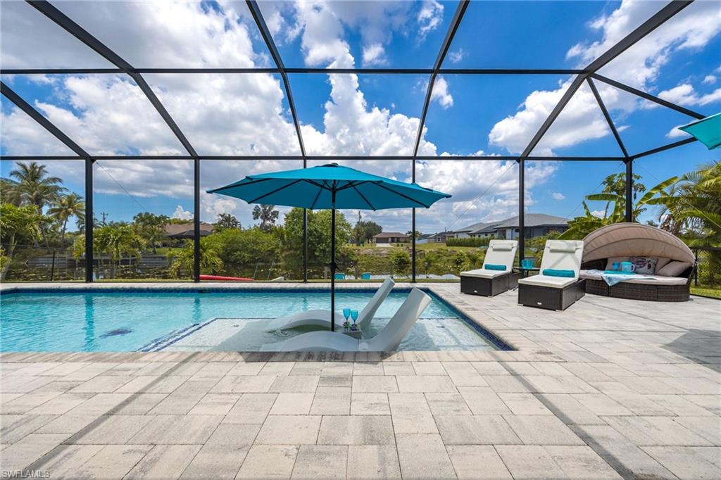 Screened lanai featuring a swimming pool with a sun shelf, paver patio, and water frontage