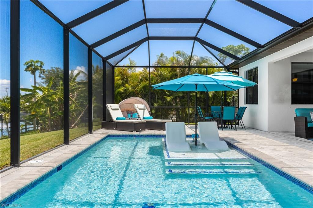 Screen-enclosed pool area featuring a rectangular swimming pool with an integrated sun shelf, paver patio, and covered lanai