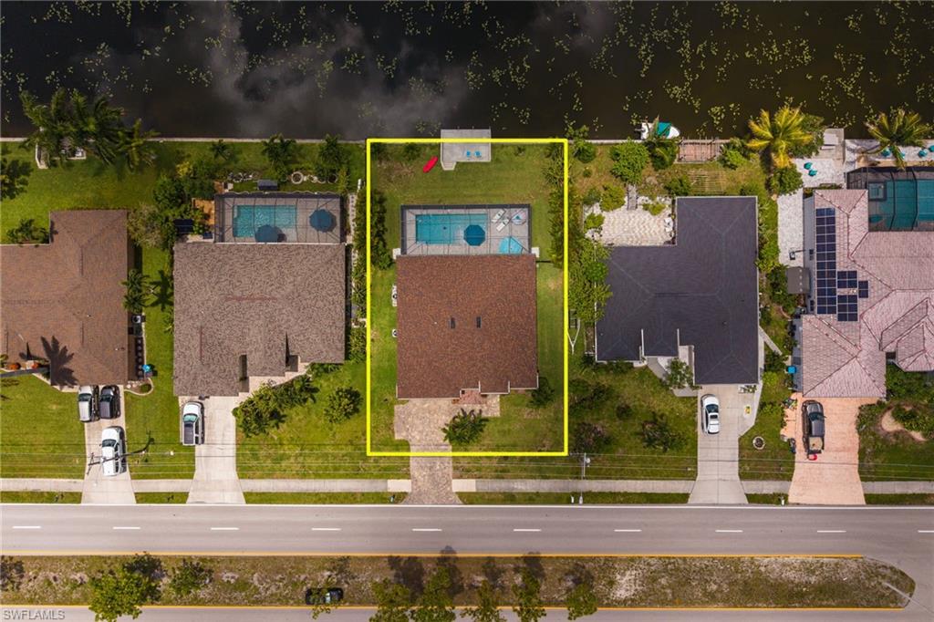Waterfront property featuring a private boat dock, screened swimming pool, and a spacious green lawn