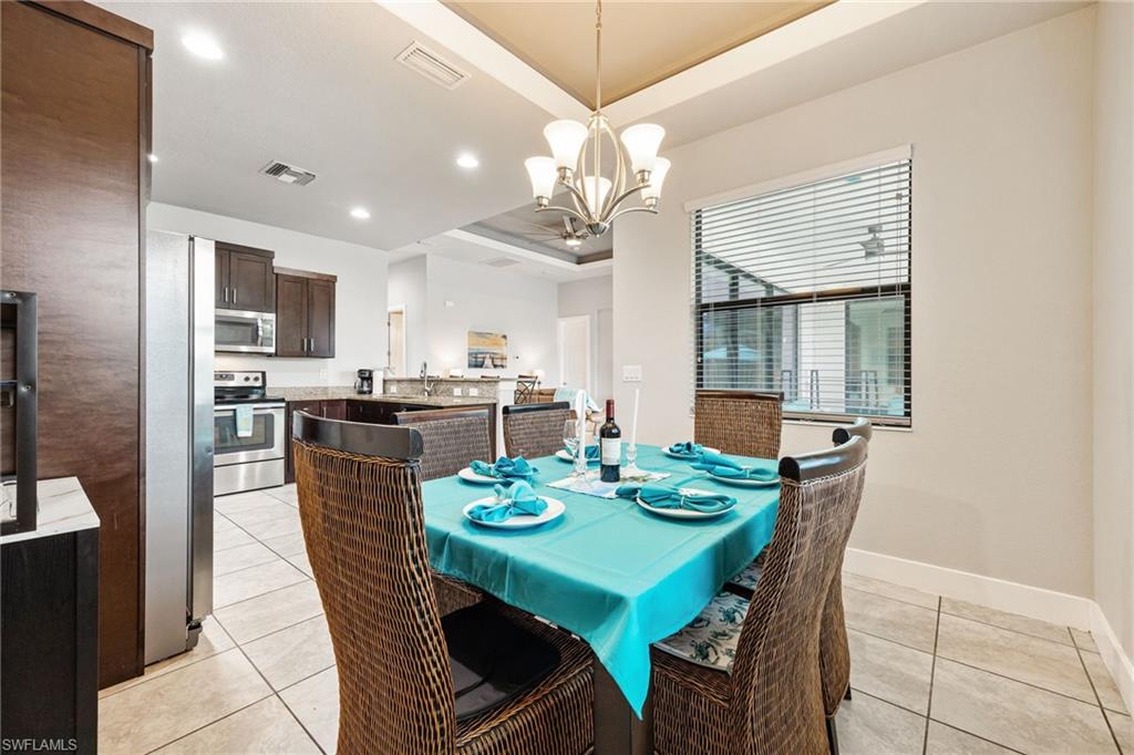 Dining area with tiled flooring, contemporary chandelier, and a window with horizontal blinds