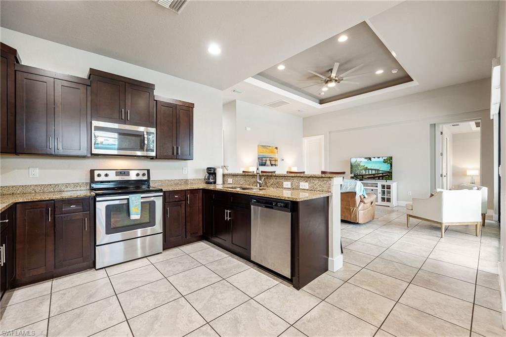 Kitchen featuring dark wood cabinetry, stainless steel appliances, granite countertops, and tile flooring