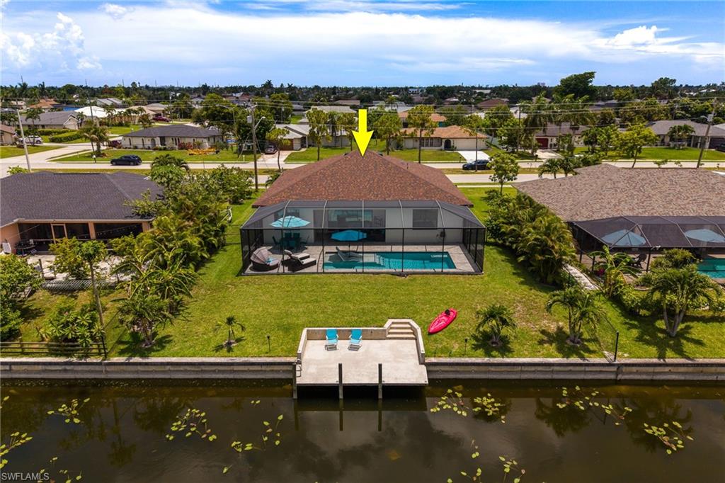 Waterfront property featuring a screened-in pool area, private dock, and mature landscaping