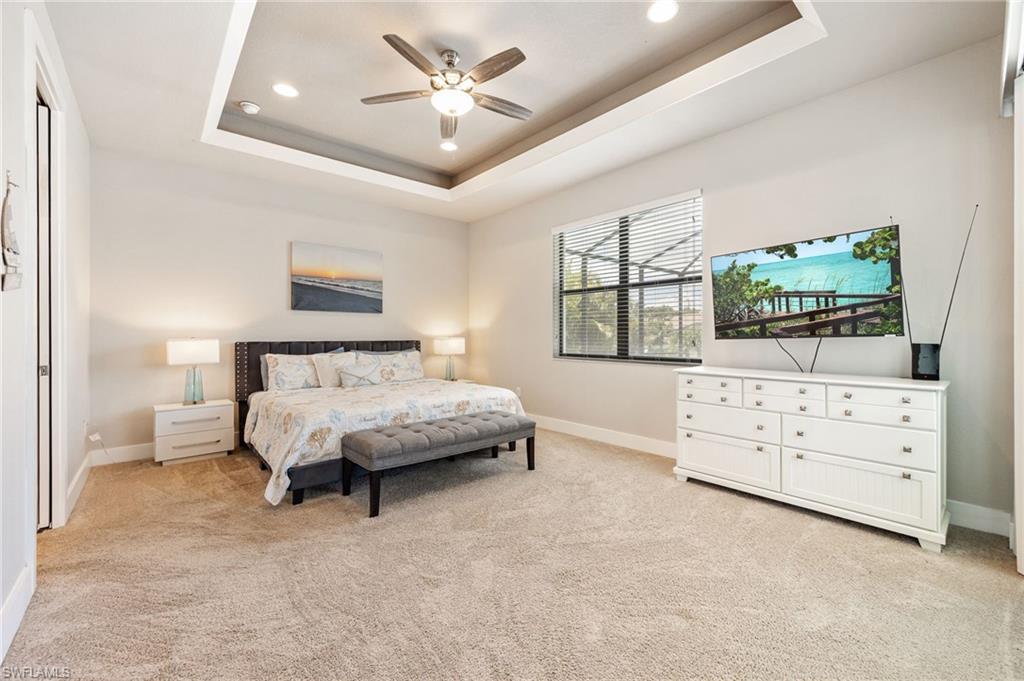Spacious bedroom featuring a tray ceiling with recessed lighting and a ceiling fan