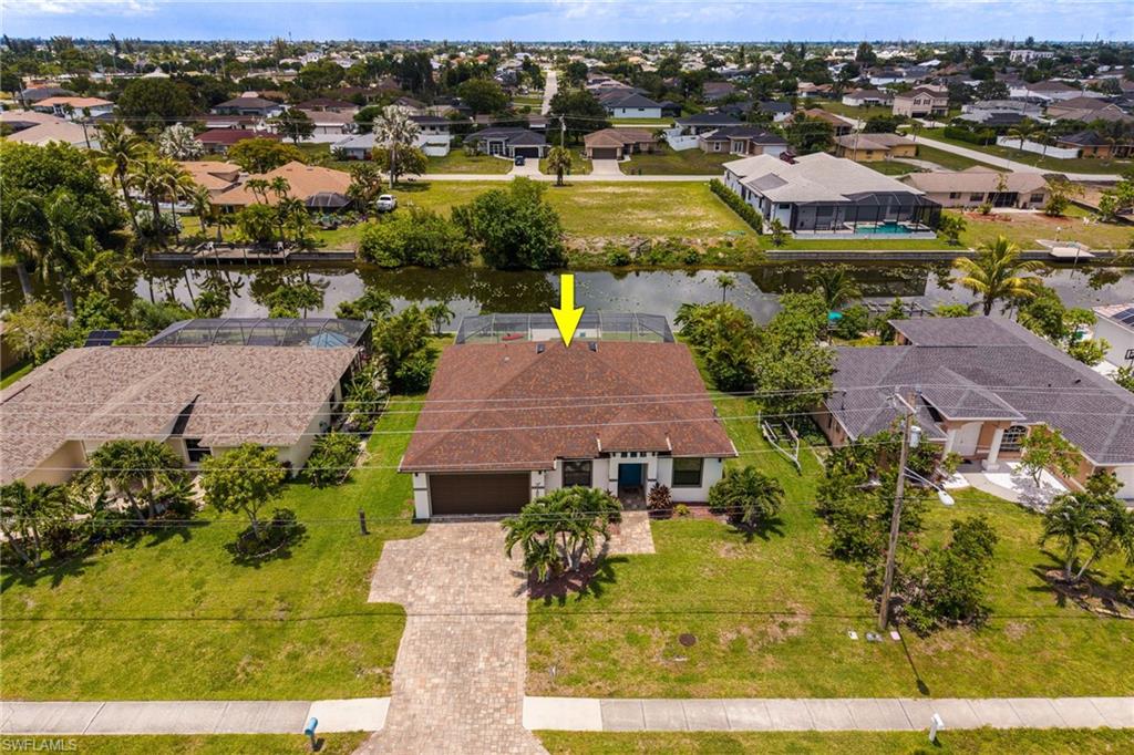 Single-story residence featuring a paved driveway, attached garage, and a canal-front setting