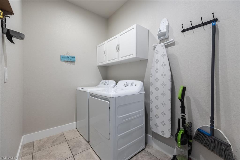Laundry area featuring light gray walls, white baseboards, and neutral-toned tile flooring
