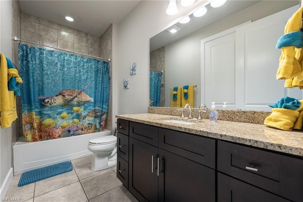 Bathroom featuring a spacious single vanity with a light-toned countertop, a large mirror, and dark wood-finish cabinetry