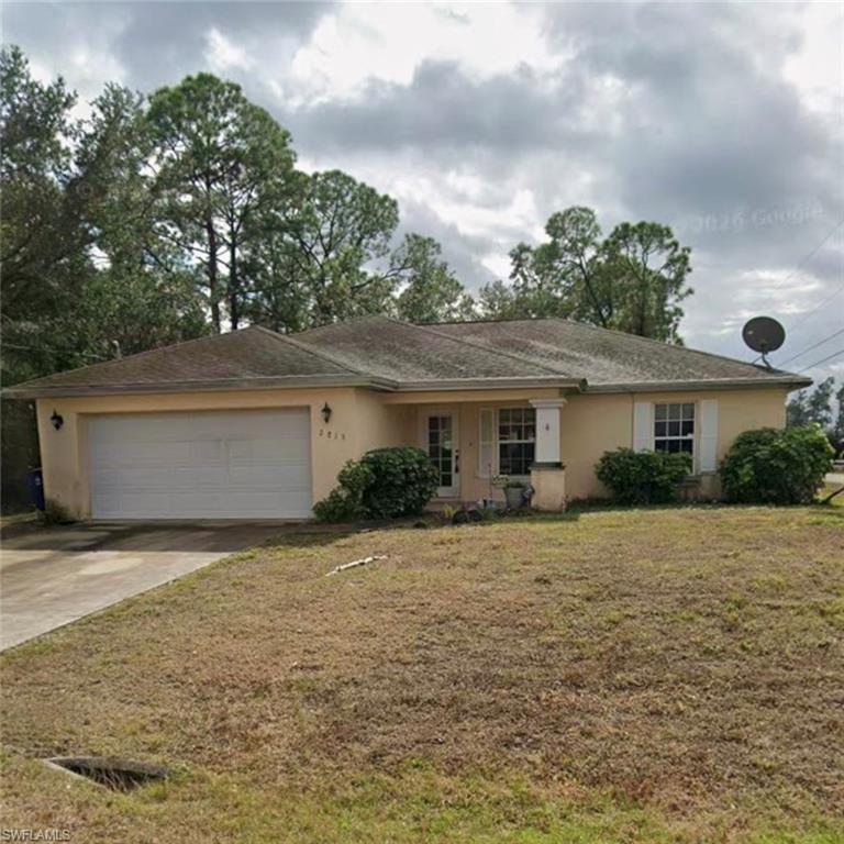 Single-story residence featuring a two-car garage, front porch with columns, and mature landscaping