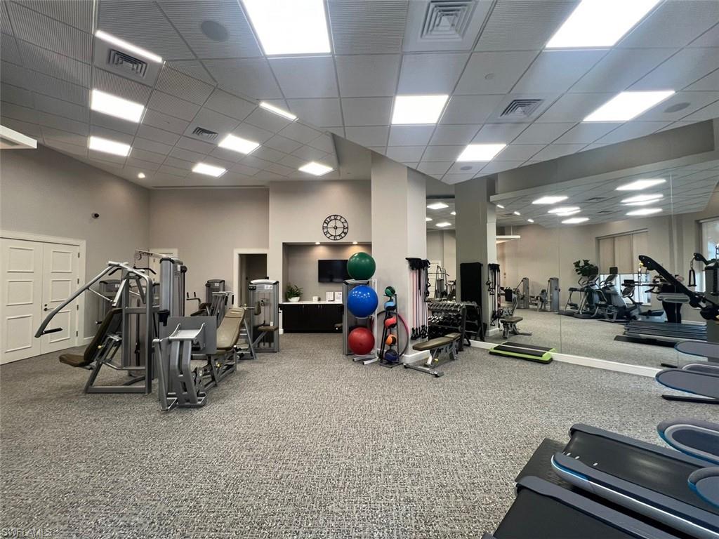 Gym with carpet flooring, a towering ceiling, and a paneled ceiling