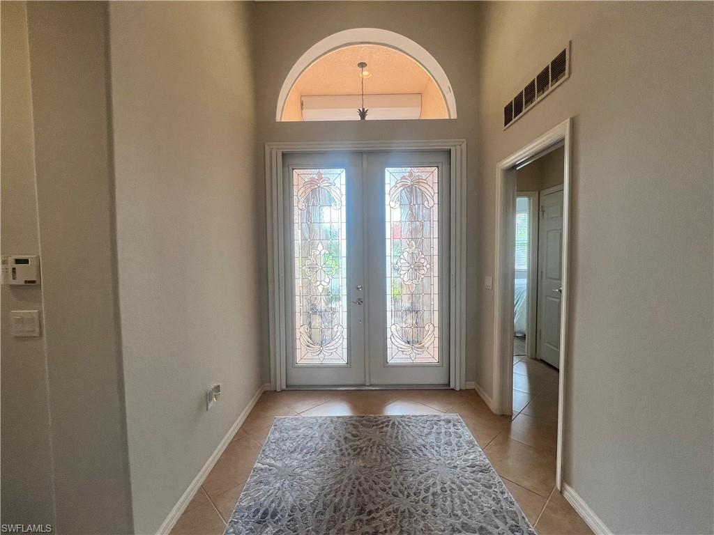 Foyer entrance with plenty of natural light, french doors, and light tile patterned flooring