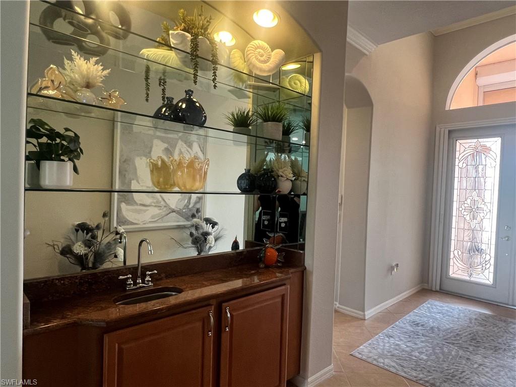 Bar with light tile patterned flooring, sink, and ornamental molding