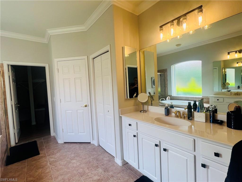 Bathroom featuring tile patterned flooring, vanity, and ornamental molding