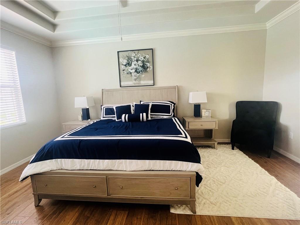 Bedroom featuring ornamental molding, a raised ceiling, and hardwood / wood-style floors