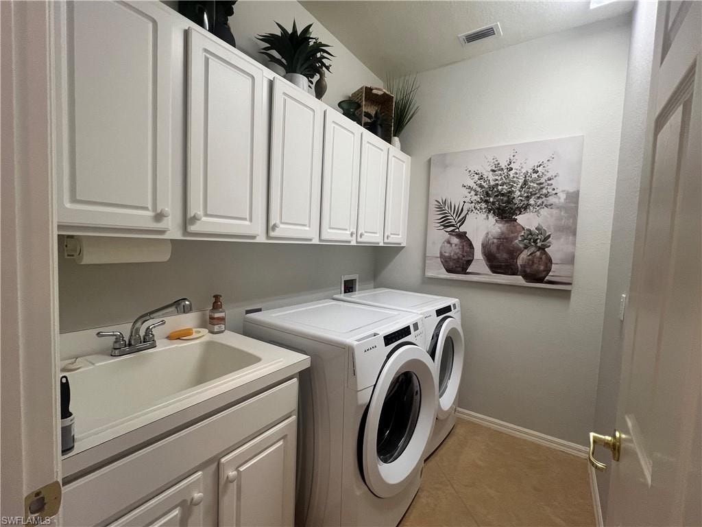 Washroom with sink, cabinets, washer and dryer, and light tile patterned floors