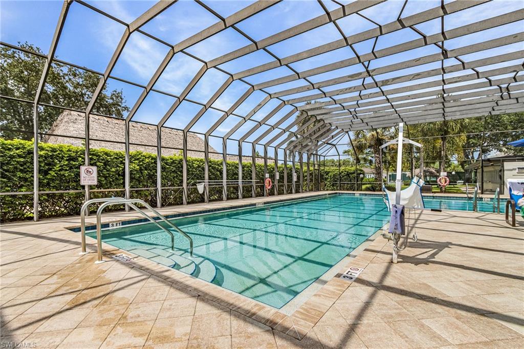 Screened swimming pool with integrated steps and stainless steel handrails, surrounded by textured tile decking.