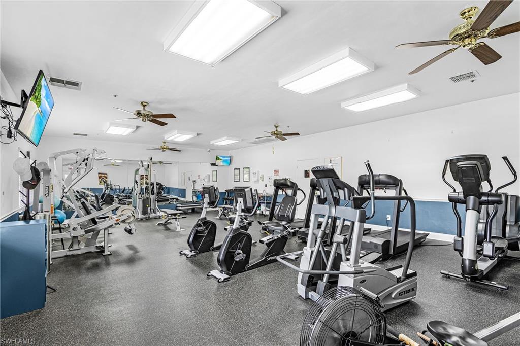 Fitness center featuring a variety of exercise equipment, ceiling fans, recessed lighting, and wall-mounted tv's.