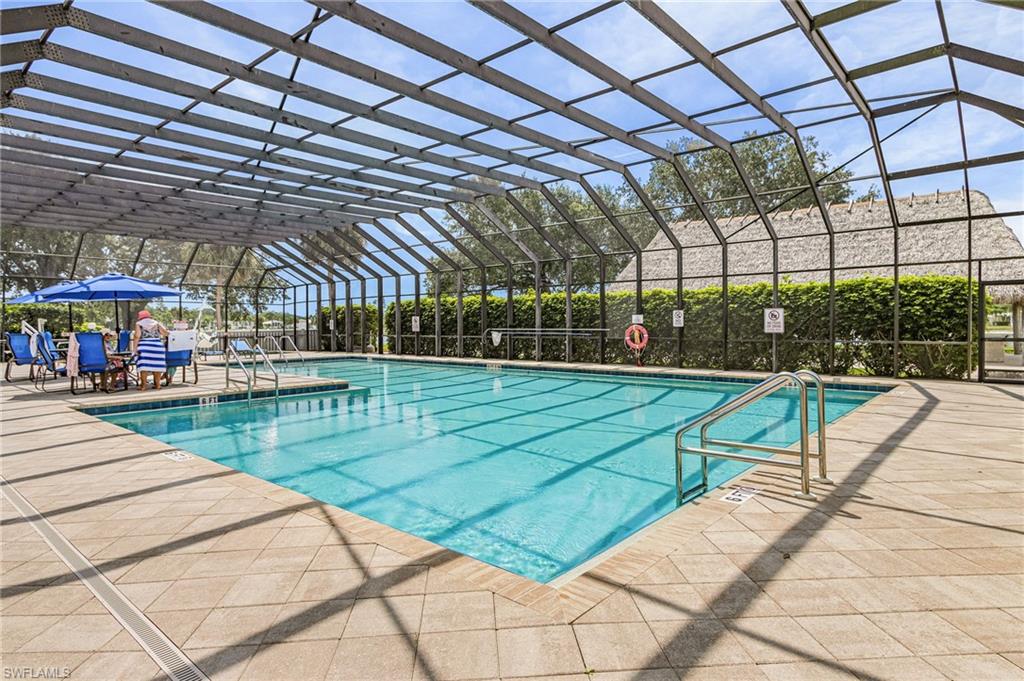 Expansive screened pool enclosure featuring a large swimming pool, surrounding paver decking, and  overhead screening.