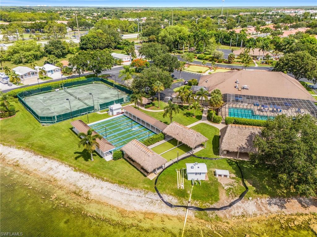 Expansive outdoor amenities featuring two tennis courts, a screened swimming pool, putting greens, and a waterside recreational building.
