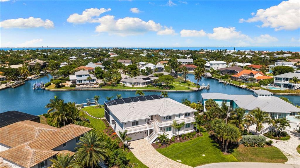 Waterfront property featuring a private boat dock, lush tropical landscaping, and a paver driveway