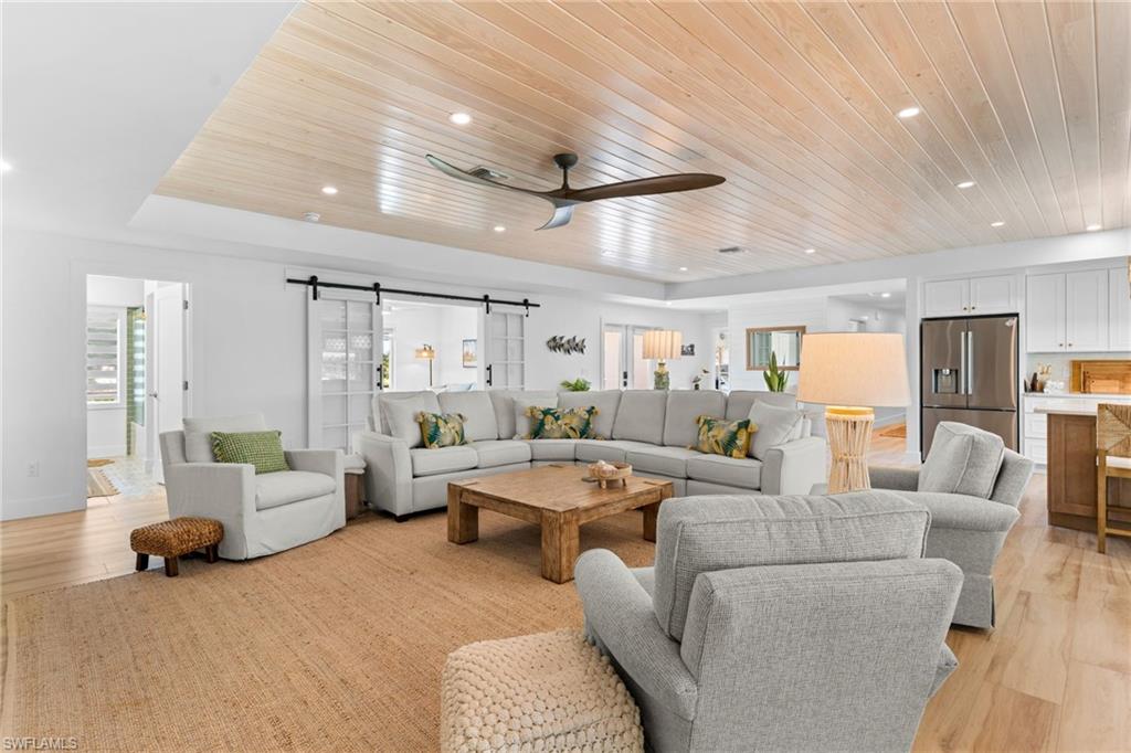 Spacious living area featuring a light wood-finish plank ceiling with recessed lighting and a ceiling fan