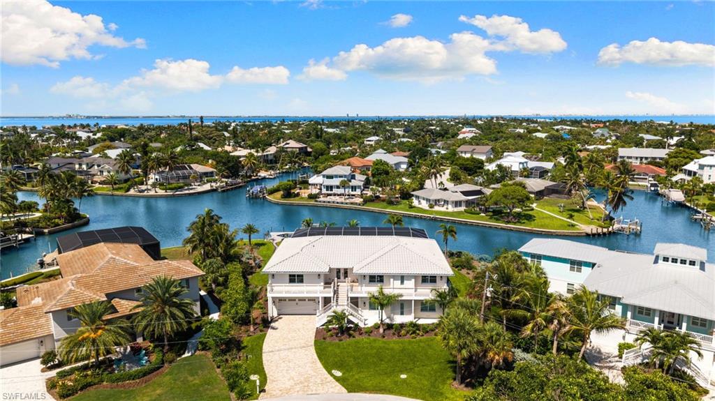 Elevated coastal residence featuring a white exterior, multiple balconies, a paver driveway, and a two-car garage