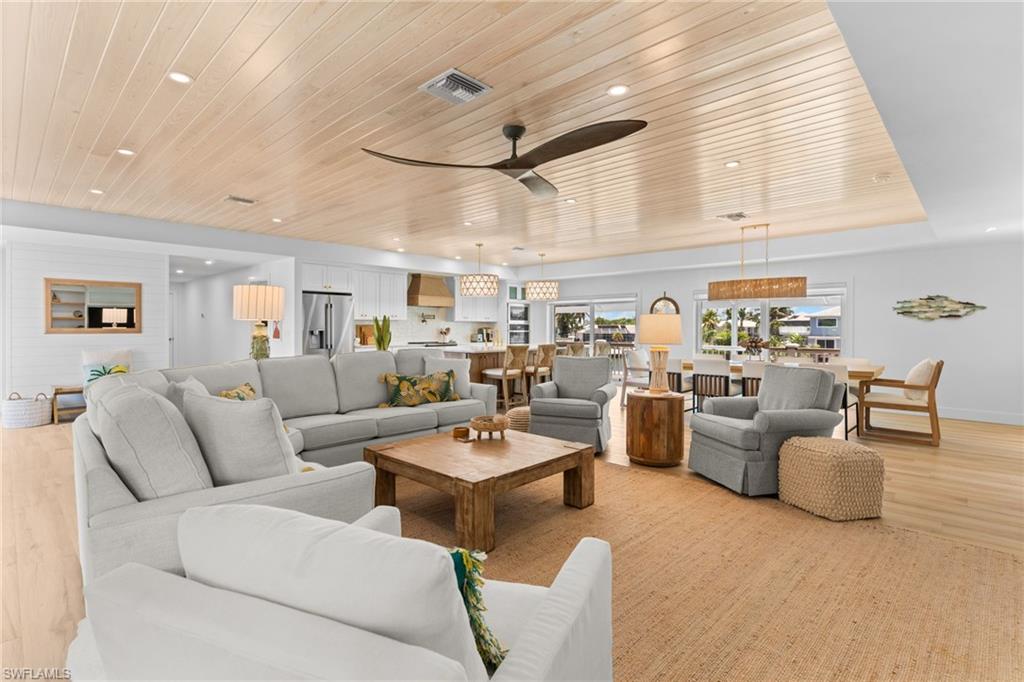 Expansive open-concept interior featuring light wood-finish flooring, a planked wood-finish ceiling with recessed lighting, and a contemporary ceiling fan