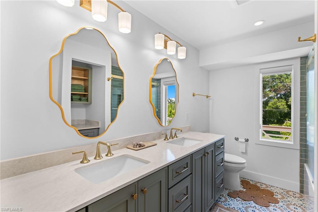 Dual vanity with light-toned countertop, under-mount sinks, and gold-finish fixtures